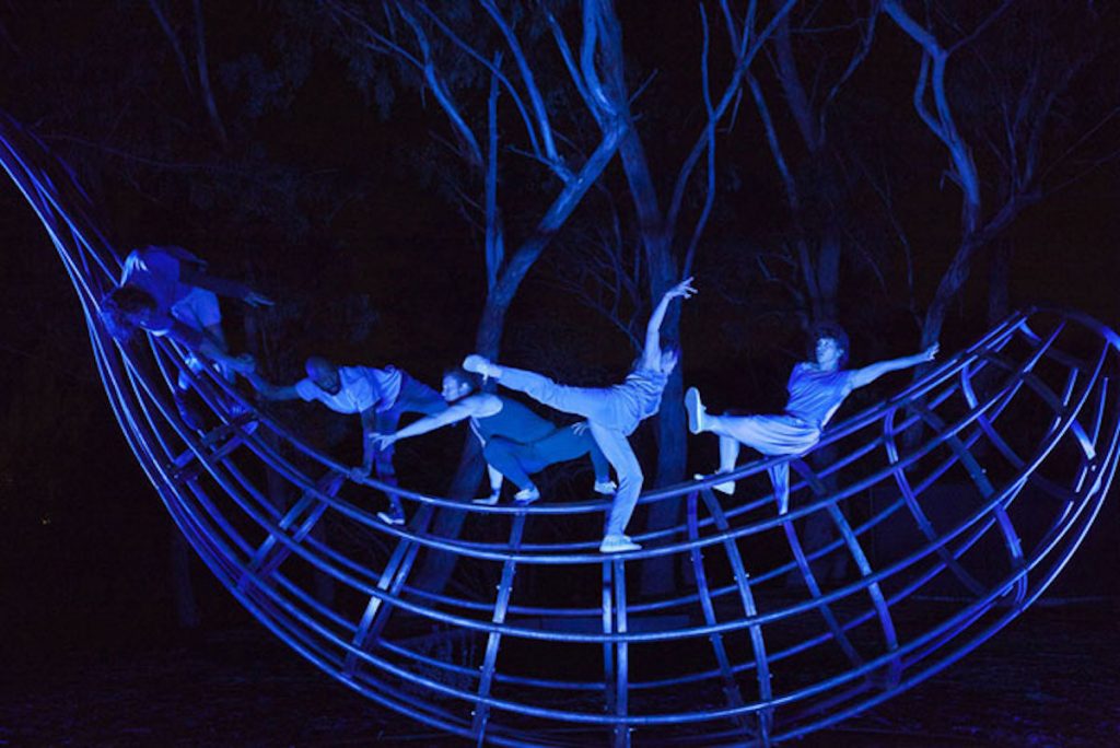 dancers pose on a fish scupture