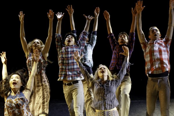 A group of dancers lift their arms