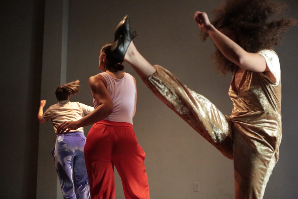 three dancers, one kicking her let up