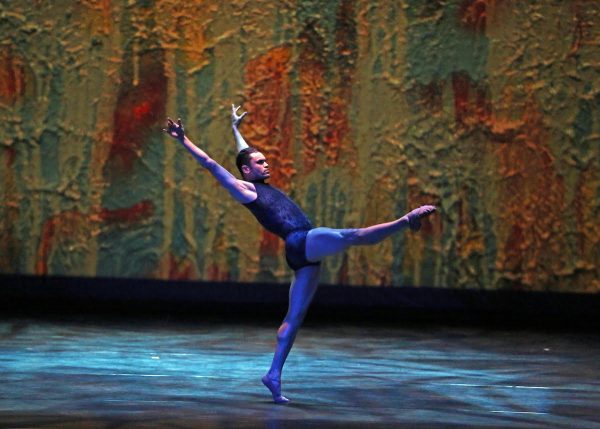A dancer in blue against a vibrant background