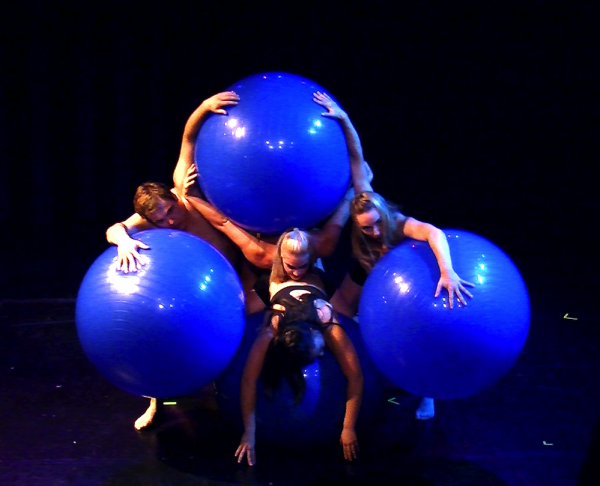 a group of dancers hold giant blue balls