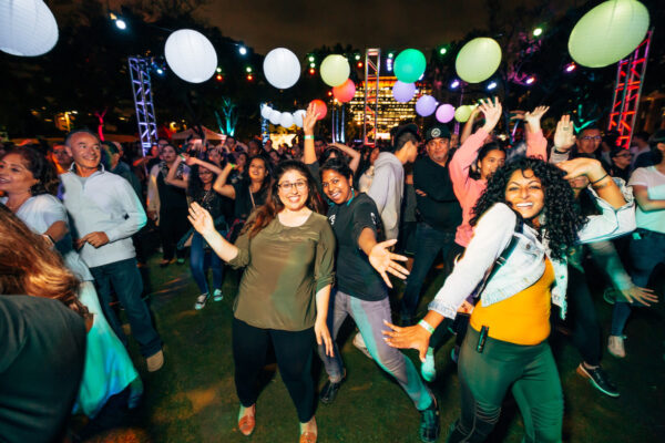 A large group of dancers beneath colored baloons