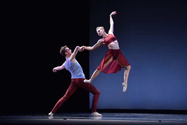 A dancer in red is lifted