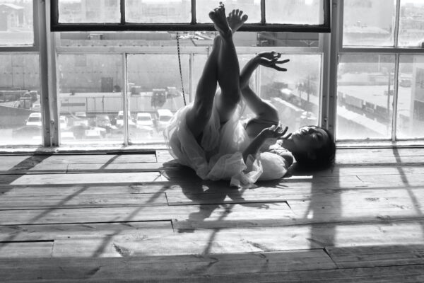 A woman lies on her back in front of window