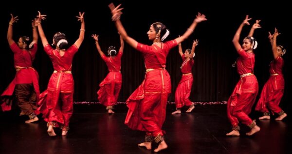 Dancers in red raise their arms