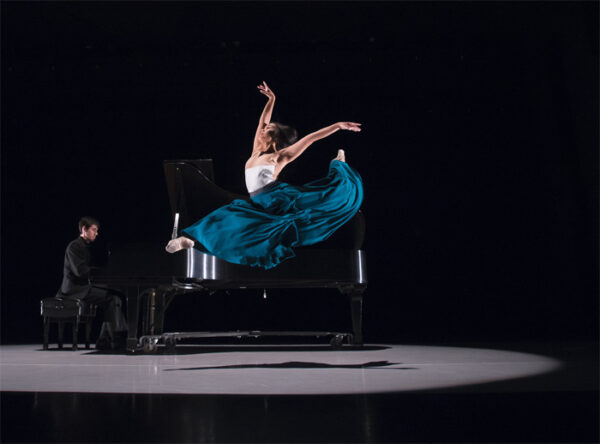 A woman in a blue skirt leaps in the air