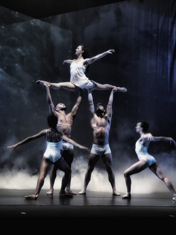 Two men hold up a dancer in the splits
