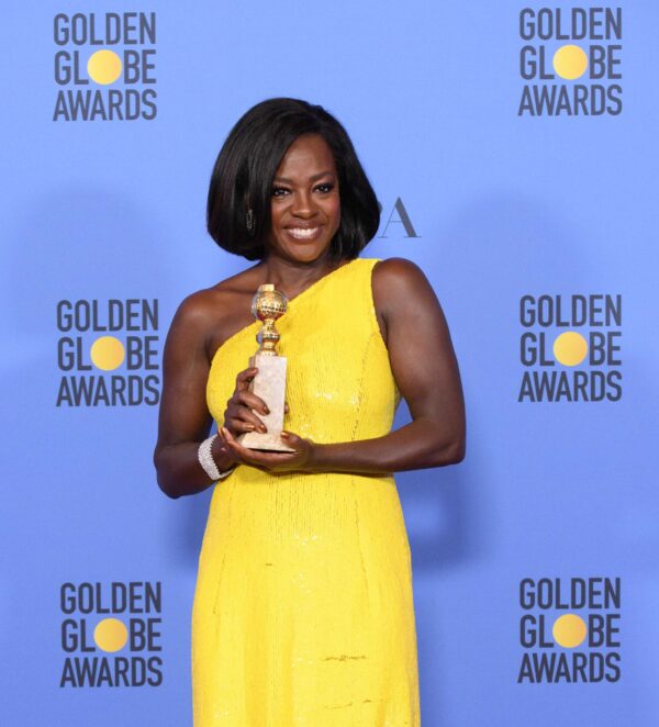 The magnificent award winning actress Viola Davis at the Golden Globe Awards, hold her trophy, dressed in a bright and stunning yellow dress.
