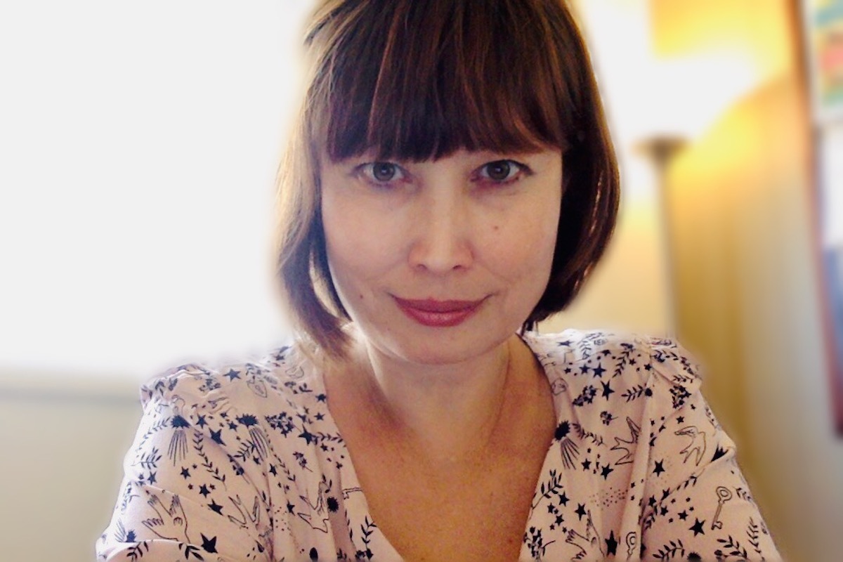 An Asian woman, the author Risa Willaims, looks directly into the camera.