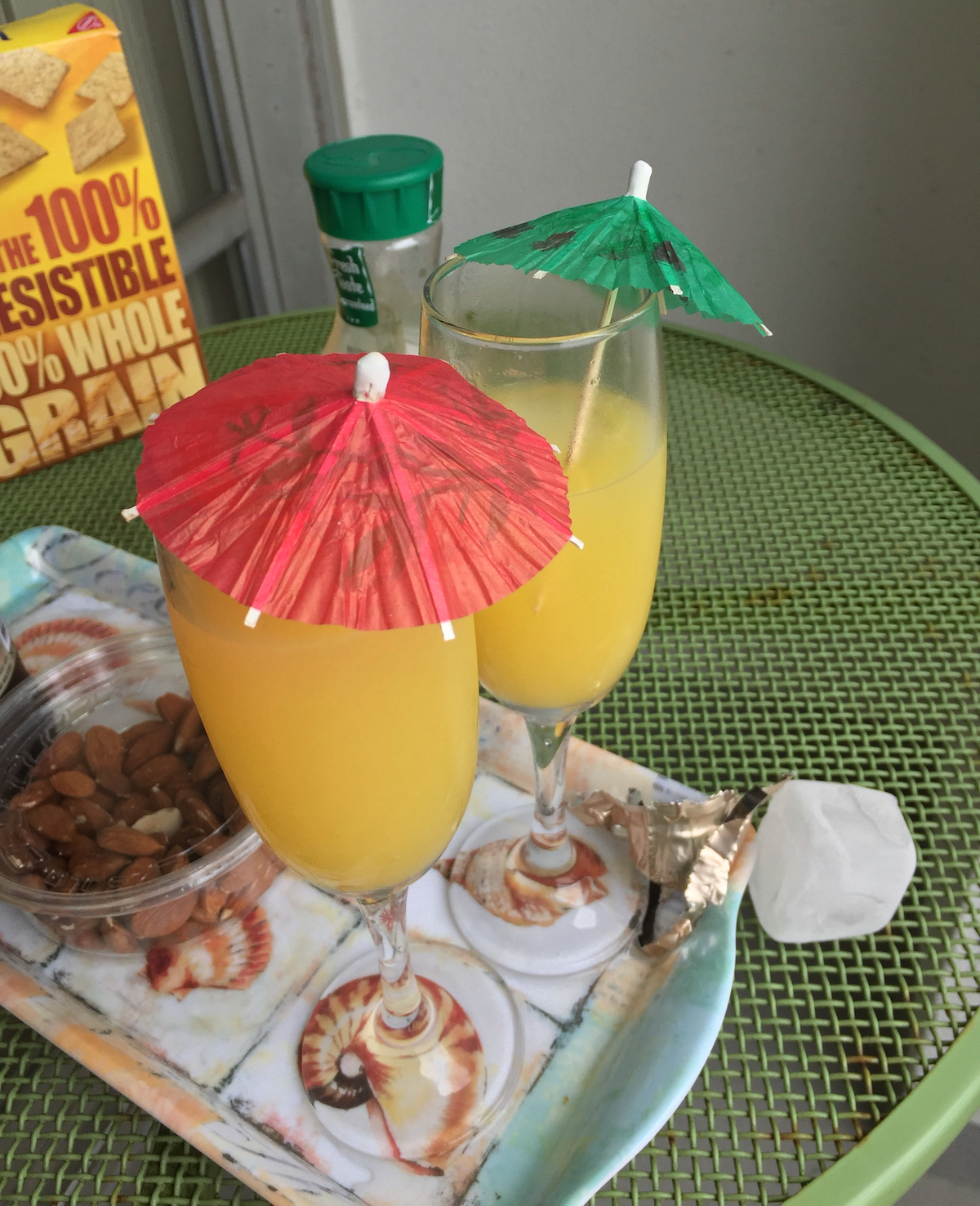 Two cocktails, yellow, with green and red paper umbrellas