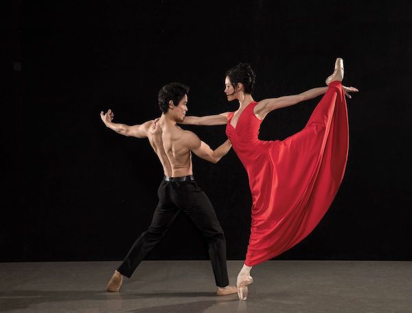 A bare-chested man dances with a woman in a long red dress for the Los Angeles Ballet