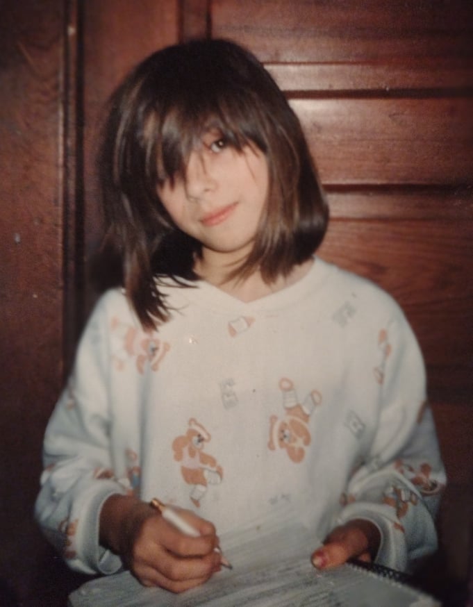 portrait of a writer as a child. a young girl in white pajamas scribbles on her paper.