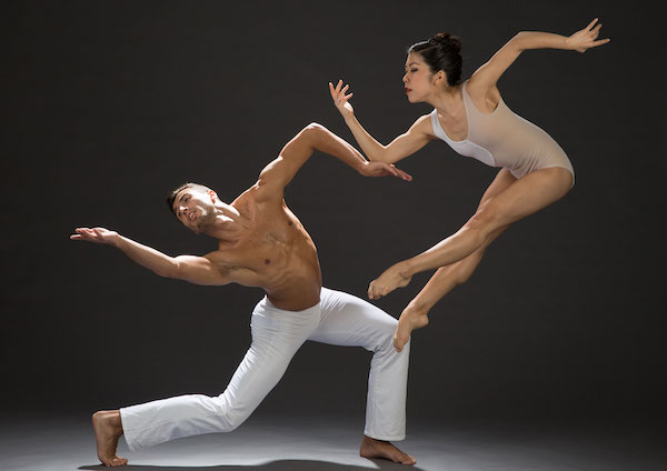 A male dancer bends backward and a woman leaps in the air