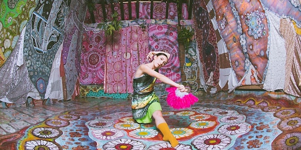 A woman with a fan sits in a colorful art installation