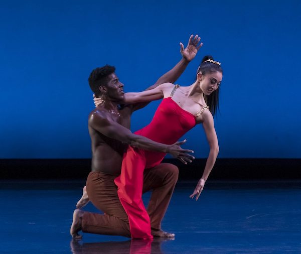 A man holds a woman in a red dress