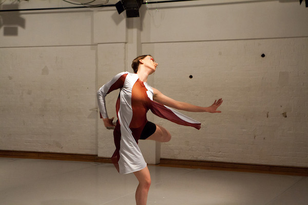 a woman dances in front of large white doors