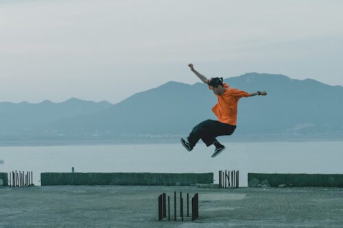 A dancer jumps against a backgroun of water and a mountain