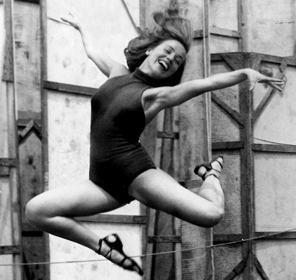 A smiling woman jumps in the air
