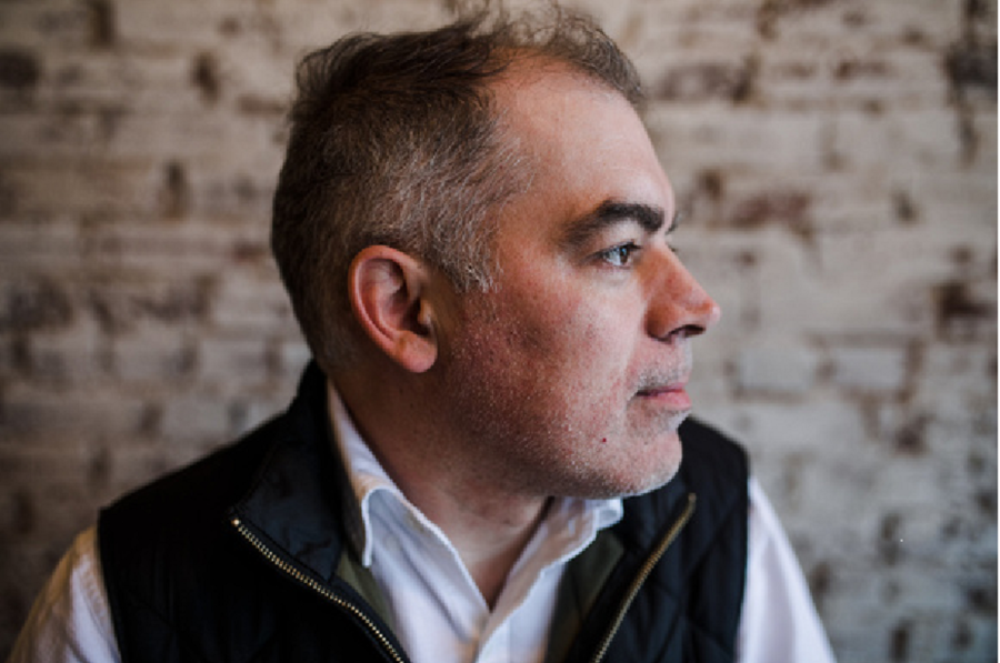 Photo of poet Nathan Spoon. He's looking to his left. Hair is short; grey on the side. Eyebrows black. 