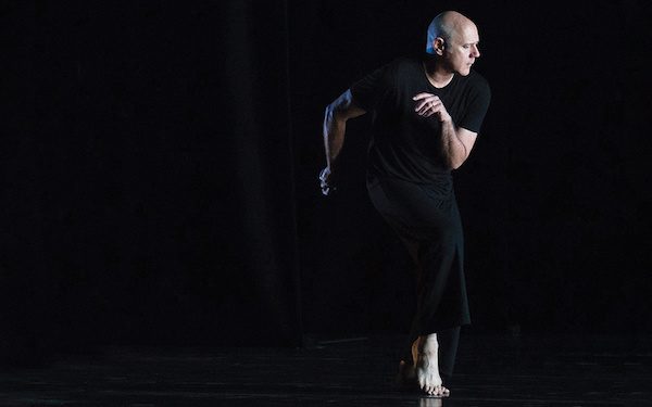 A man in black looks offstage