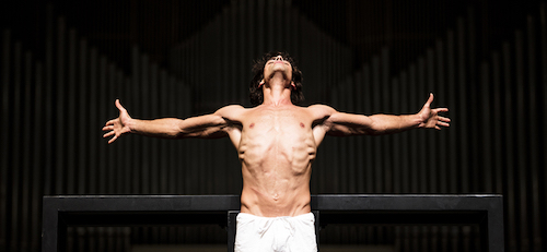 A bare-chested man spreads his arms