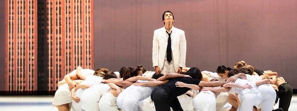 A group kneels around a man in a white suit