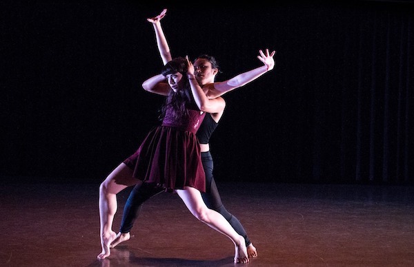 A male dancer holds a woman who raises her arms
