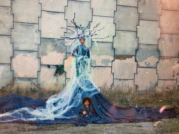 A woman in a long blue dress with a child at the bottom