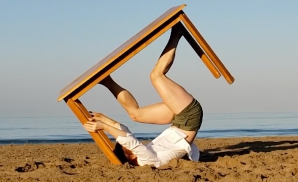 A dancer on his back holds up a table with his legs