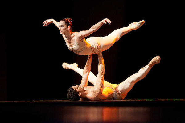 A man on his back lifts a woman dancer