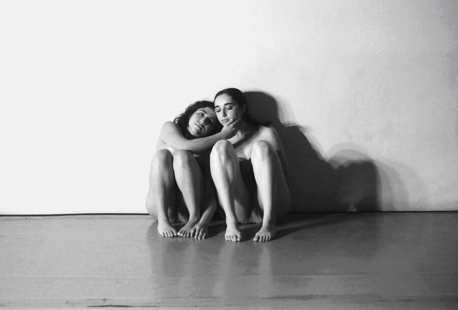 Two women sitting against a wall
