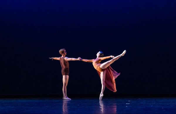 A male dancer holds a female dancer in arabesque