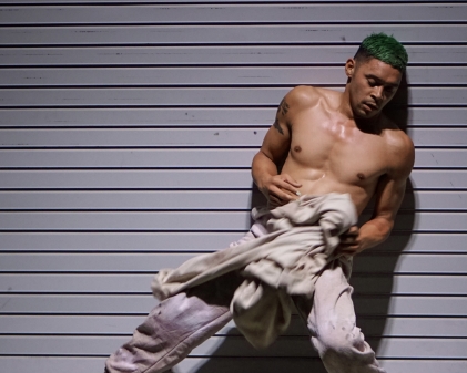 A man without shirt against a wall