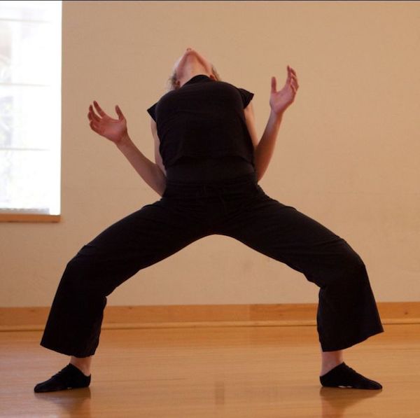 A dancer in black bends back
