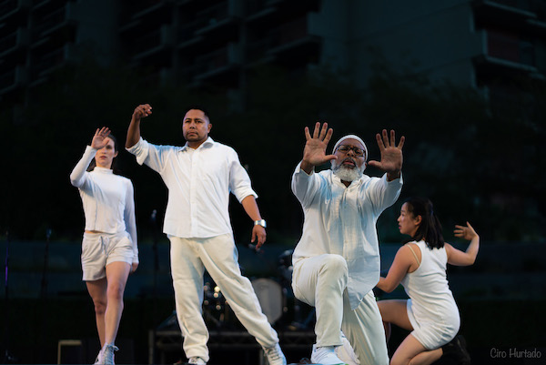 Dancers in white with arms raised