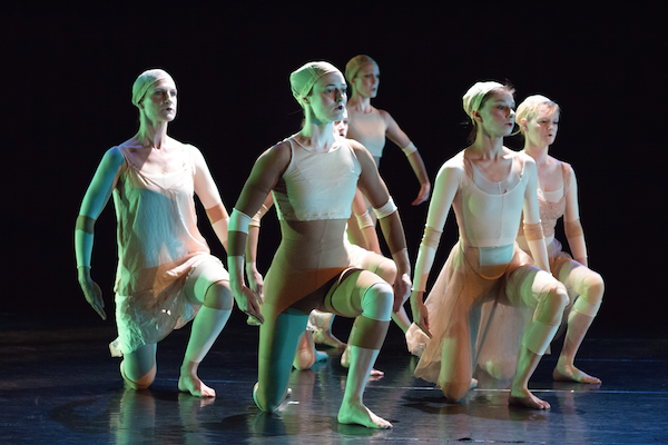 A group of dancers in white kneel