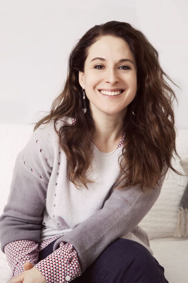 A woman with long dark hair looks at the camera