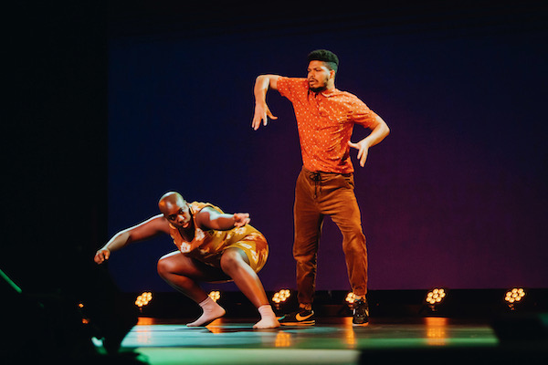 One dancer squats and another stands up