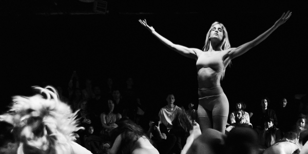 A blond dancer is lifted in a dark room
