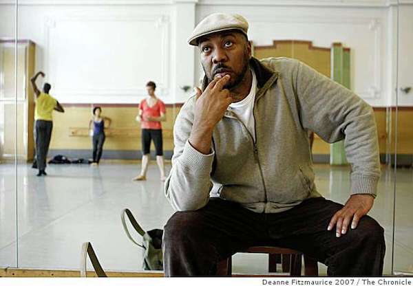 A man in a white jacket watches dancers