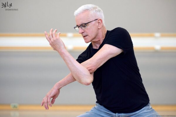 Val Caniparoli in black shirt crosses his arms