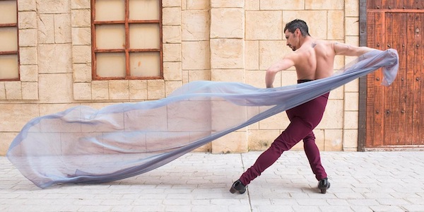A man in red pants draws a long scarf behind him
