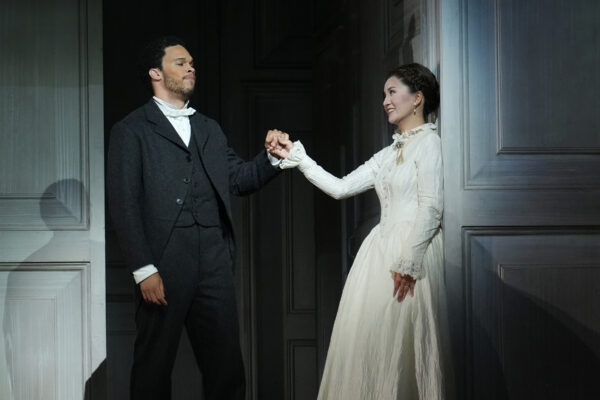 A woman in white smiles at a man holding her hand