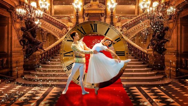 Two ballet dancers pose before a clock