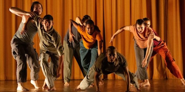 A group lunges in front of a gold curtain