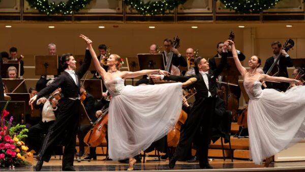 A dancer in white before an orchestra