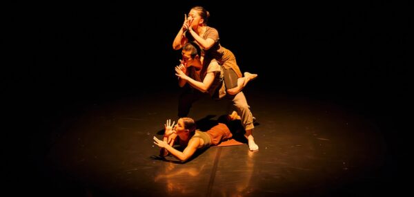 Three dancers cover their mouths