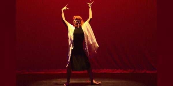 A woman in black and white lifts her arms