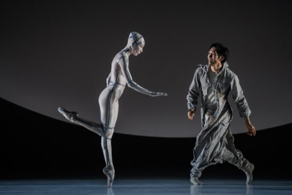A dancer in silver is viewed by a male dancer