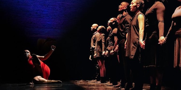 a line of dancers with a women in red on the floor